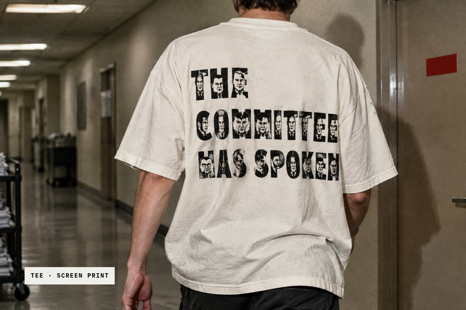 Politician Faces print on a white t-shirt reading THE COMMITTEE HAS SPOKEN, worn in an office corridor