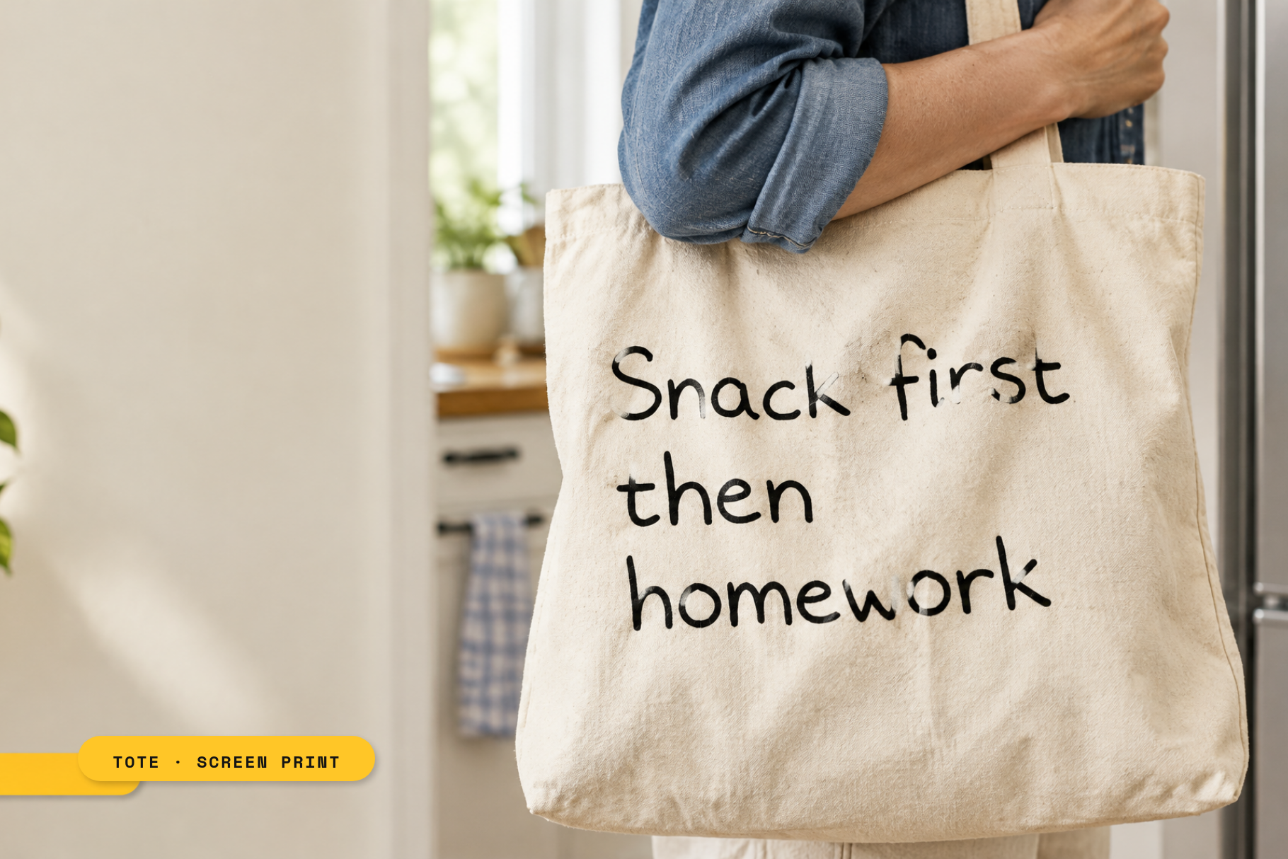 Canvas tote bag mockup screen-printed with "Snack first then homework" in Lunchbox Note, black ink on natural cotton